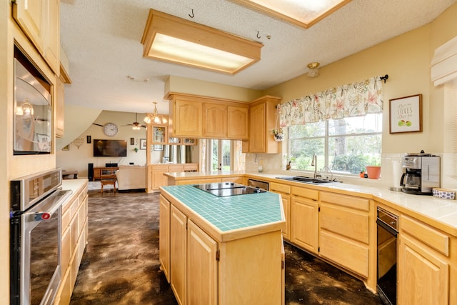 kitchen with light brown cabinetry, a center island, stainless steel oven, and sink