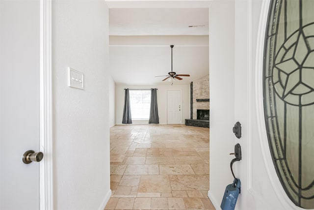 entryway with a large fireplace, vaulted ceiling, and ceiling fan