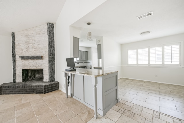 kitchen featuring lofted ceiling, light stone countertops, a fireplace, gray cabinets, and decorative light fixtures