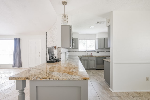 kitchen featuring sink, hanging light fixtures, stainless steel dishwasher, gray cabinets, and light stone counters