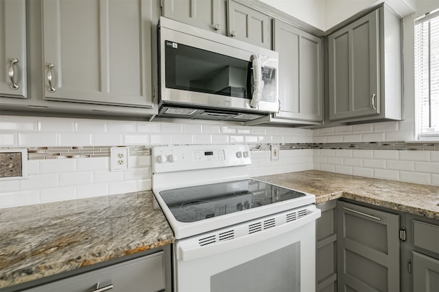 kitchen featuring gray cabinets, decorative backsplash, light stone countertops, and white electric stove