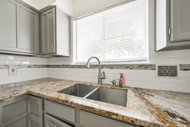 kitchen with light stone counters, gray cabinetry, and plenty of natural light