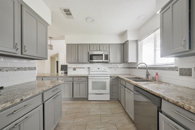 kitchen featuring gray cabinets, sink, appliances with stainless steel finishes, and decorative backsplash