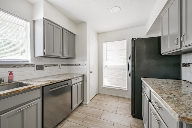 kitchen featuring gray cabinets, dishwasher, and light stone countertops