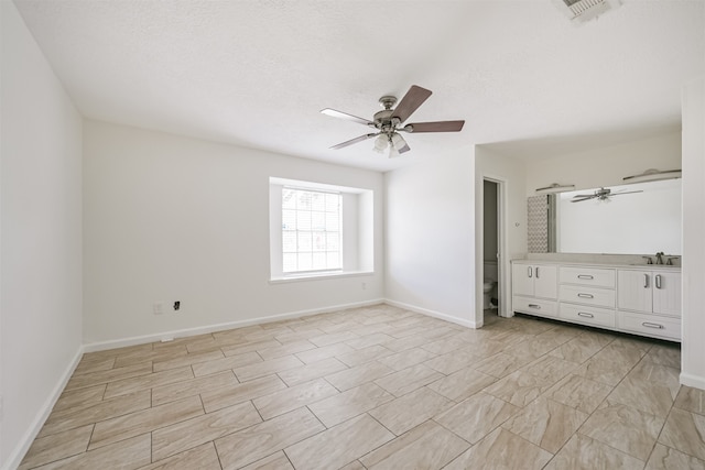 unfurnished bedroom with sink, a textured ceiling, and ceiling fan