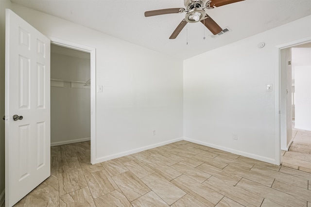 unfurnished bedroom featuring a spacious closet, a closet, and ceiling fan