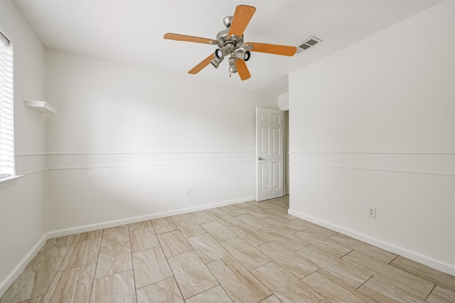 unfurnished room with ceiling fan and a textured ceiling