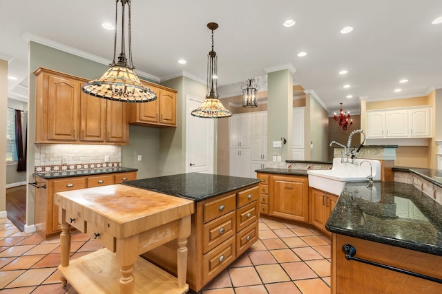 kitchen featuring dark stone countertops, light tile patterned floors, hanging light fixtures, and ornamental molding