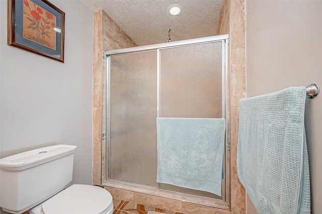 bathroom featuring toilet, a textured ceiling, and a shower with shower door