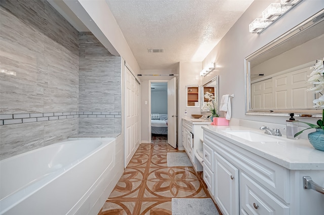 bathroom with tile patterned flooring, a washtub, a textured ceiling, and vanity