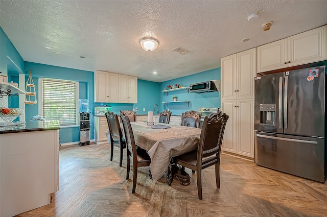 dining room featuring light parquet flooring and a textured ceiling