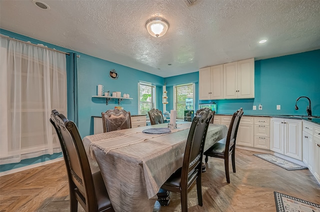 dining area with light parquet floors, sink, and a textured ceiling