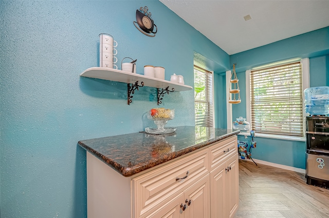 kitchen featuring light parquet flooring, white cabinets, and dark stone counters