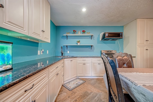 kitchen featuring white cabinetry, light parquet flooring, a textured ceiling, and sink