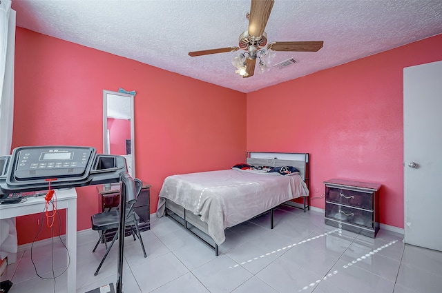 bedroom with a textured ceiling, light tile patterned floors, and ceiling fan