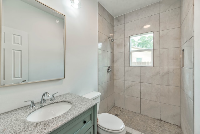 bathroom with vanity, toilet, and a tile shower