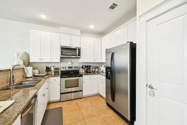 kitchen with white cabinets, dark stone countertops, backsplash, appliances with stainless steel finishes, and sink