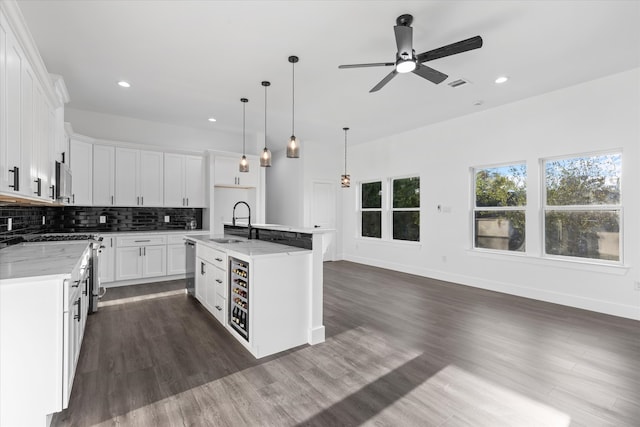 kitchen featuring a center island with sink, white cabinetry, light stone countertops, and ceiling fan