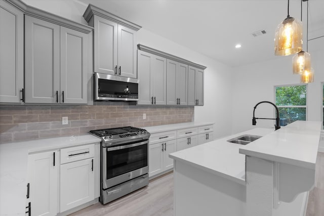 kitchen featuring sink, decorative light fixtures, stainless steel appliances, light wood-type flooring, and decorative backsplash