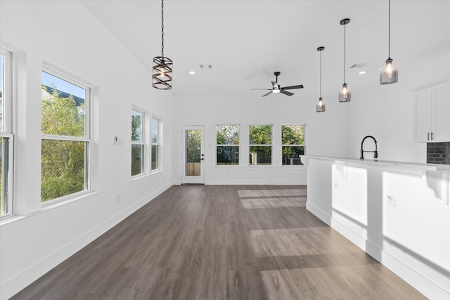 unfurnished living room featuring a high ceiling, ceiling fan, dark hardwood / wood-style floors, and sink