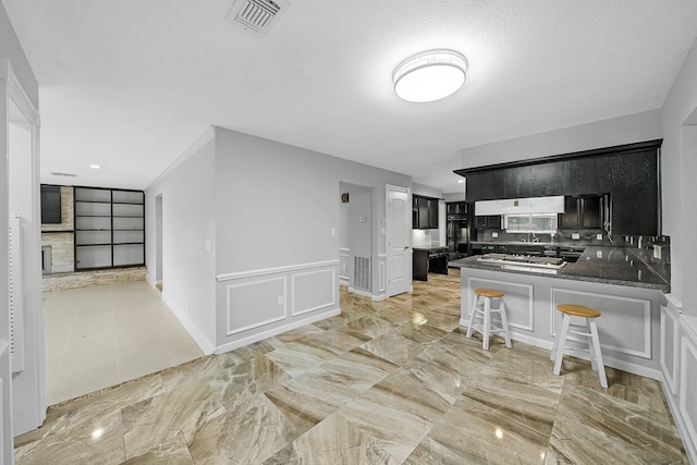 kitchen featuring a kitchen bar, a textured ceiling, kitchen peninsula, and backsplash