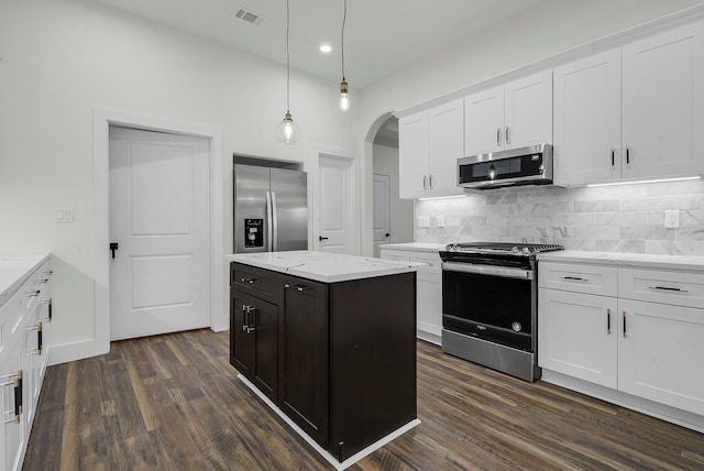 kitchen featuring white cabinetry, stainless steel appliances, dark hardwood / wood-style flooring, light stone counters, and hanging light fixtures