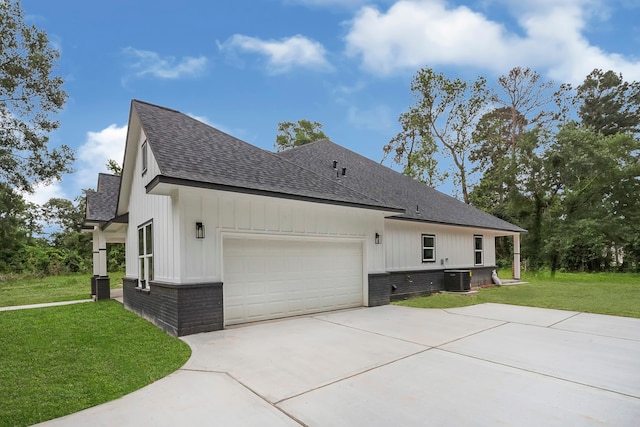 view of side of property with central air condition unit, a lawn, and a garage