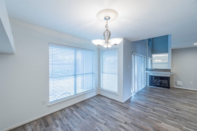 unfurnished living room with a fireplace, hardwood / wood-style floors, a chandelier, and a wealth of natural light