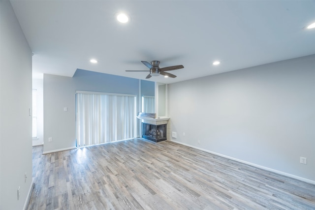 unfurnished living room with light hardwood / wood-style floors, a multi sided fireplace, and ceiling fan