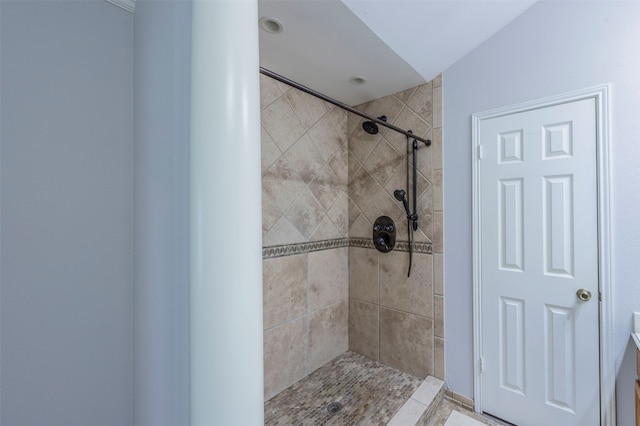 bathroom with tiled shower and lofted ceiling