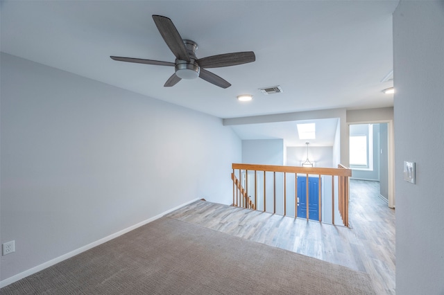 spare room with ceiling fan, a skylight, and hardwood / wood-style flooring