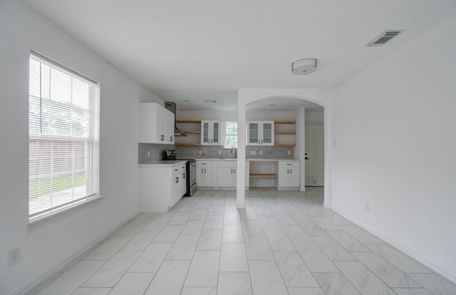 kitchen featuring plenty of natural light, backsplash, white cabinets, and stainless steel range with electric cooktop