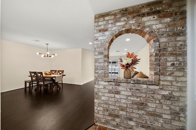 hallway with recessed lighting, wood finished floors, arched walkways, and a chandelier