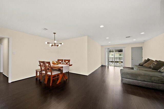 dining space with dark wood-type flooring and an inviting chandelier