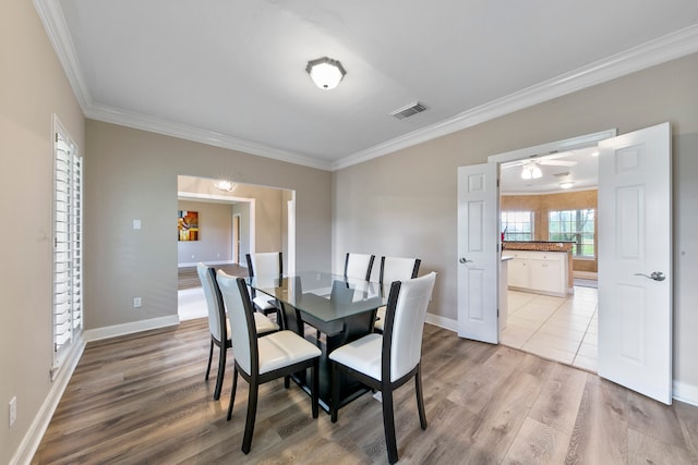 dining room featuring light wood-type flooring, ornamental molding, and ceiling fan