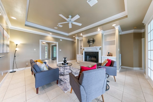 living room featuring ceiling fan, light tile patterned floors, a raised ceiling, and ornamental molding