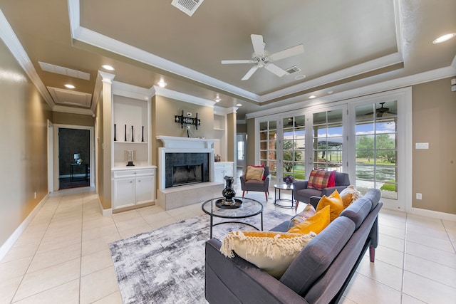 tiled living room featuring a raised ceiling, ceiling fan, ornamental molding, and a fireplace