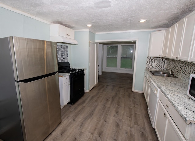 2620 W Shane St, Alvin, TX 77511 - kitchen with freestanding refrigerator, gas stove, under cabinet range hood, decorative backsplash, and a textured ceiling