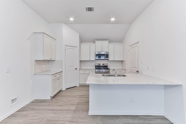 kitchen with appliances with stainless steel finishes, white cabinetry, sink, and light hardwood / wood-style floors