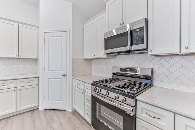 kitchen featuring light stone countertops, backsplash, light hardwood / wood-style floors, stainless steel appliances, and white cabinetry