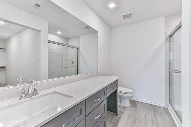 bathroom featuring vanity, toilet, hardwood / wood-style floors, and a shower with shower door