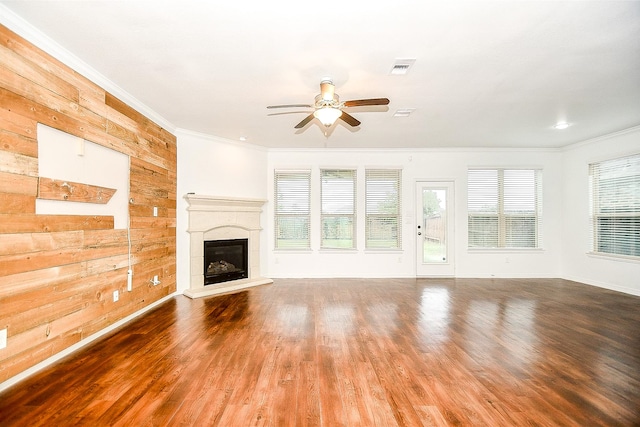 unfurnished living room with crown molding, ceiling fan, wood walls, and wood-type flooring