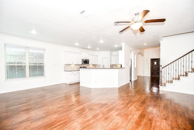 unfurnished living room featuring ceiling fan, ornamental molding, and light wood-type flooring