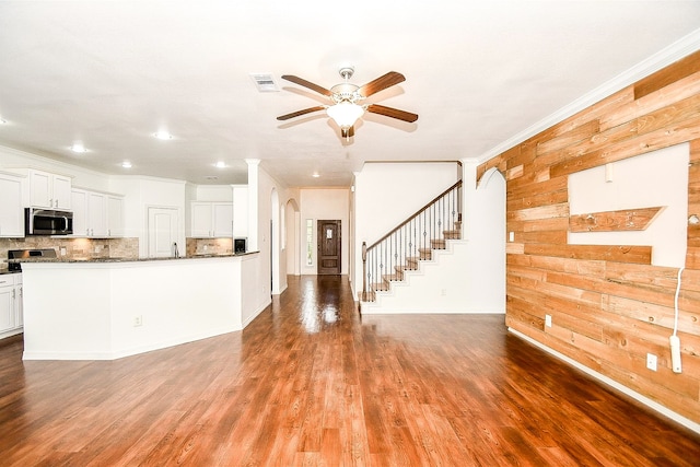 kitchen with white cabinets, hardwood / wood-style flooring, wooden walls, crown molding, and ceiling fan