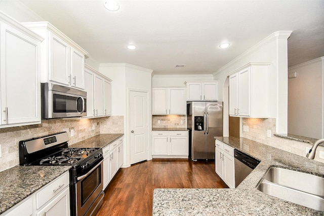 kitchen with dark hardwood / wood-style floors, appliances with stainless steel finishes, ornamental molding, sink, and white cabinetry