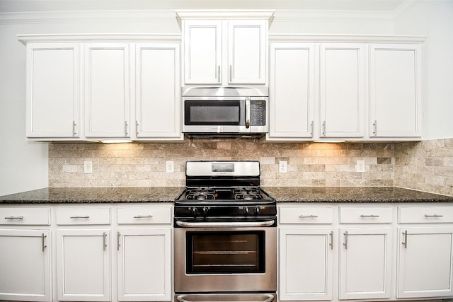 kitchen featuring dark stone countertops, backsplash, crown molding, appliances with stainless steel finishes, and white cabinetry