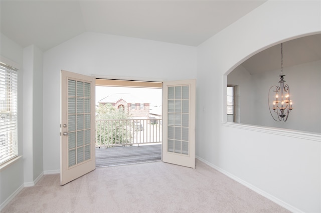 carpeted spare room with french doors, vaulted ceiling, a chandelier, and a healthy amount of sunlight