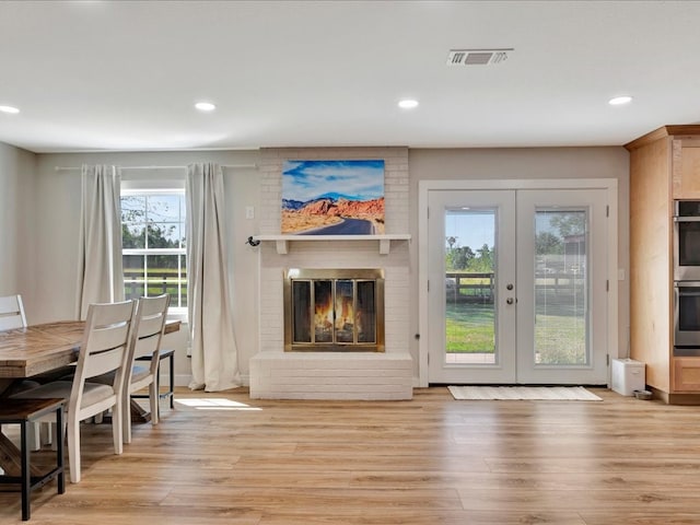 living room featuring light hardwood / wood-style flooring, a fireplace, and french doors