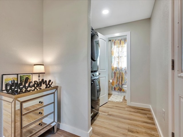 laundry area featuring light hardwood / wood-style flooring and stacked washer / dryer