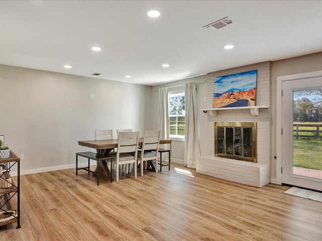 dining room featuring light wood-type flooring and a fireplace